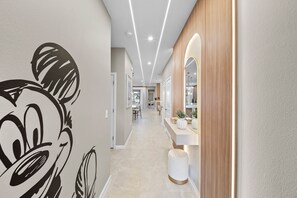 Un couloir moderne agrémenté d’une grande fresque murale, d’un éclairage encastré et d’un mur d’accent en bois.