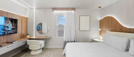 A modern hotel room with a large bed, a TV mounted on the wall, a bedside table, a mirror, and a window with curtains.