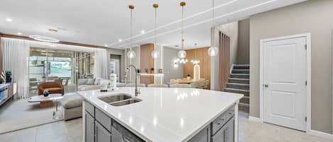A modern kitchen with a central island, stainless steel appliances, and pendant lighting.