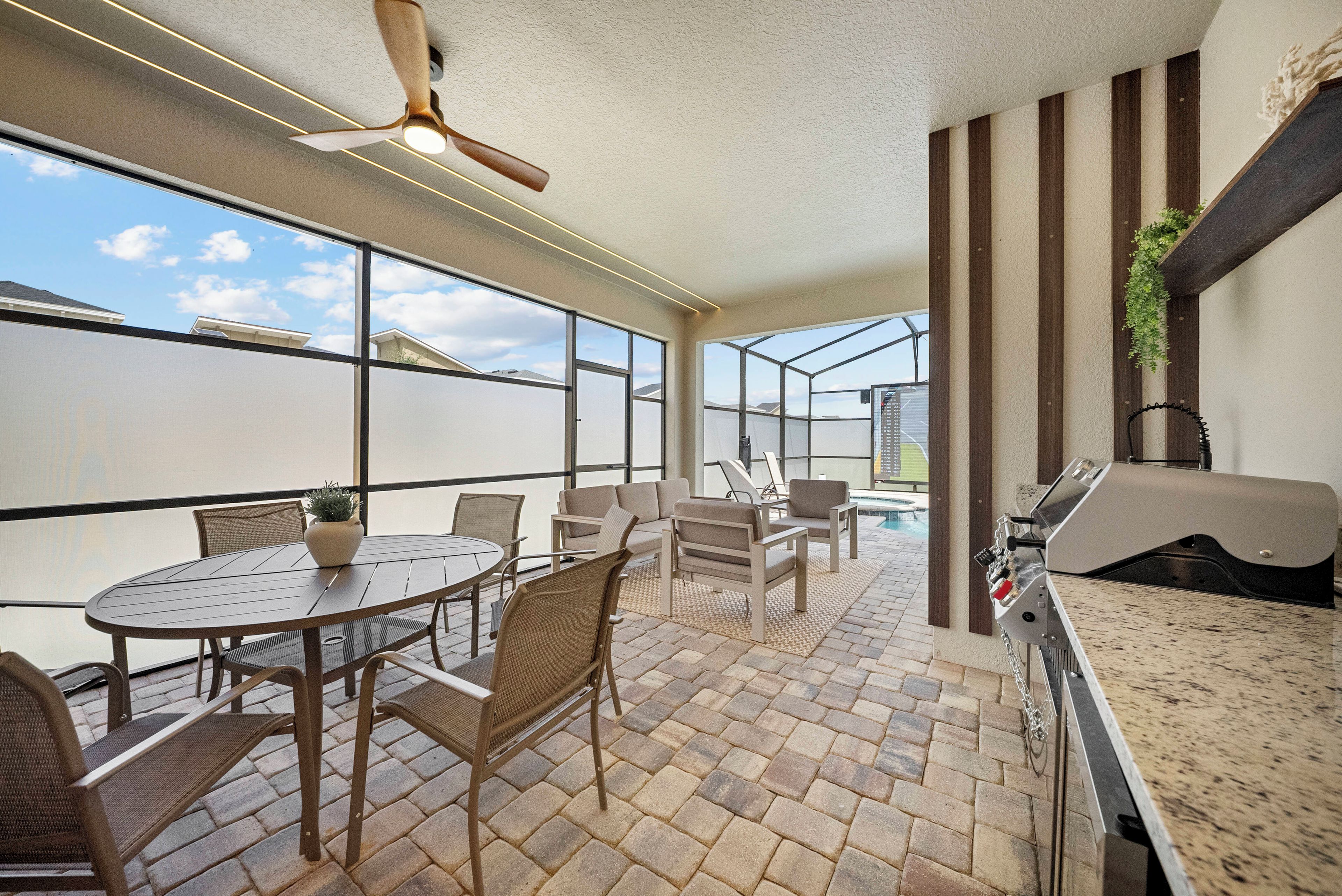 Une terrasse avec une table ronde, des chaises et un espace barbecue.