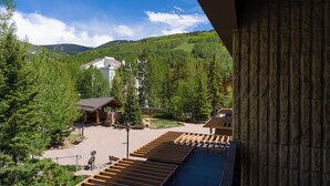 Blick auf ein Resort mit Poolbereich, Holzterrasse und einem Gebäude mit geneigtem Dach.