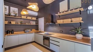 Una cocina moderna con estantes de madera, horno empotrado y cafetera.