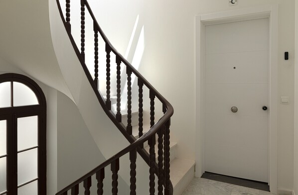 Una escalera de caracol con barandilla de madera y una puerta blanca al final.