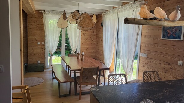 Un intérieur en bois avec une table à manger, des chaises et des lampes en rotin suspendues.