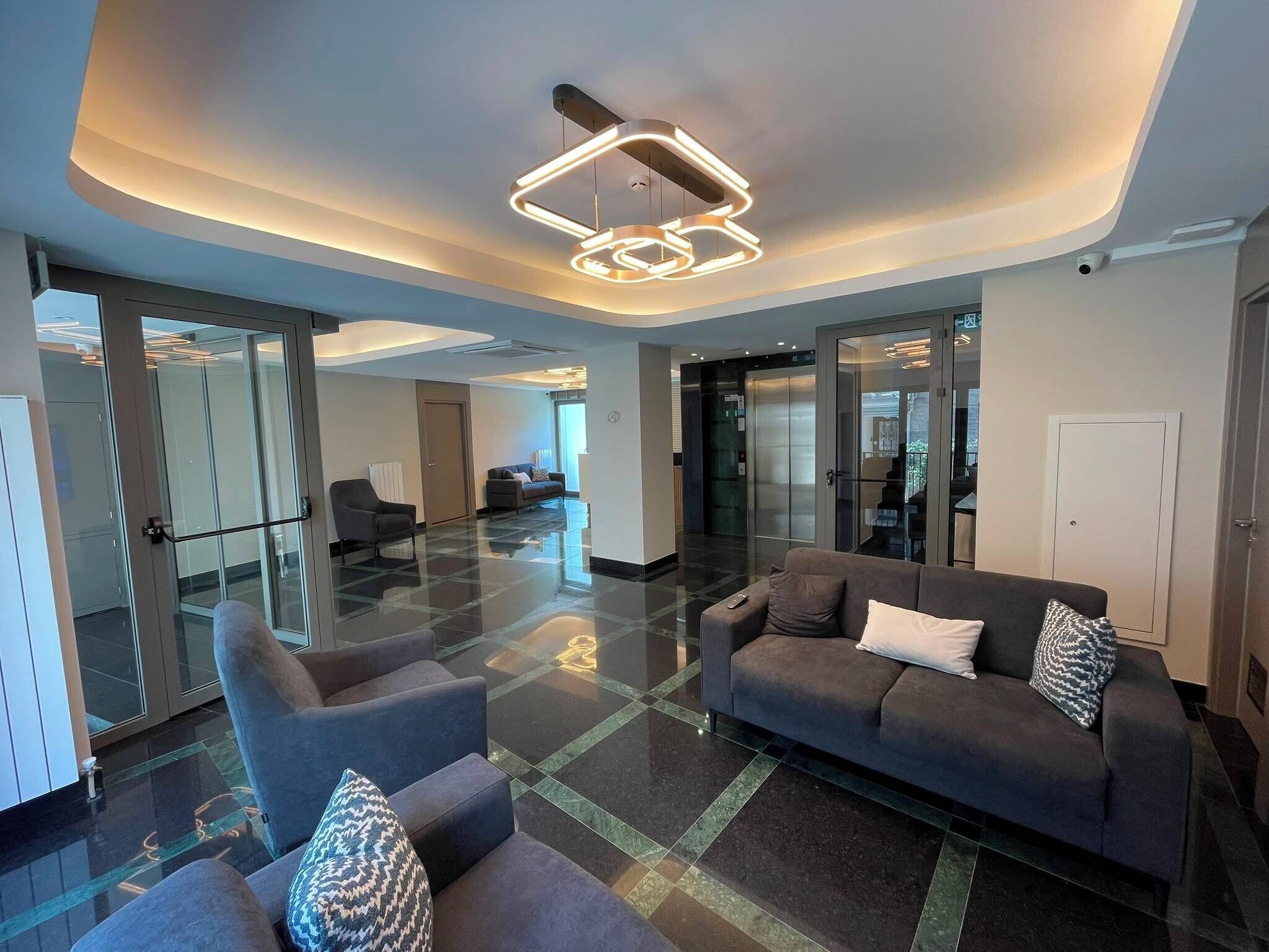 A modern lobby with a glass partition, a sofa, and a contemporary light fixture.