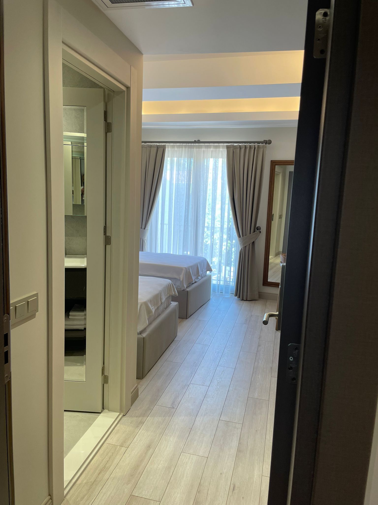 A bedroom with a bed, a walk-in closet, and a large window with curtains.