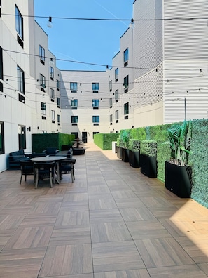 Un patio con mobiliario exterior, una pared verde y un edificio de diseño moderno.