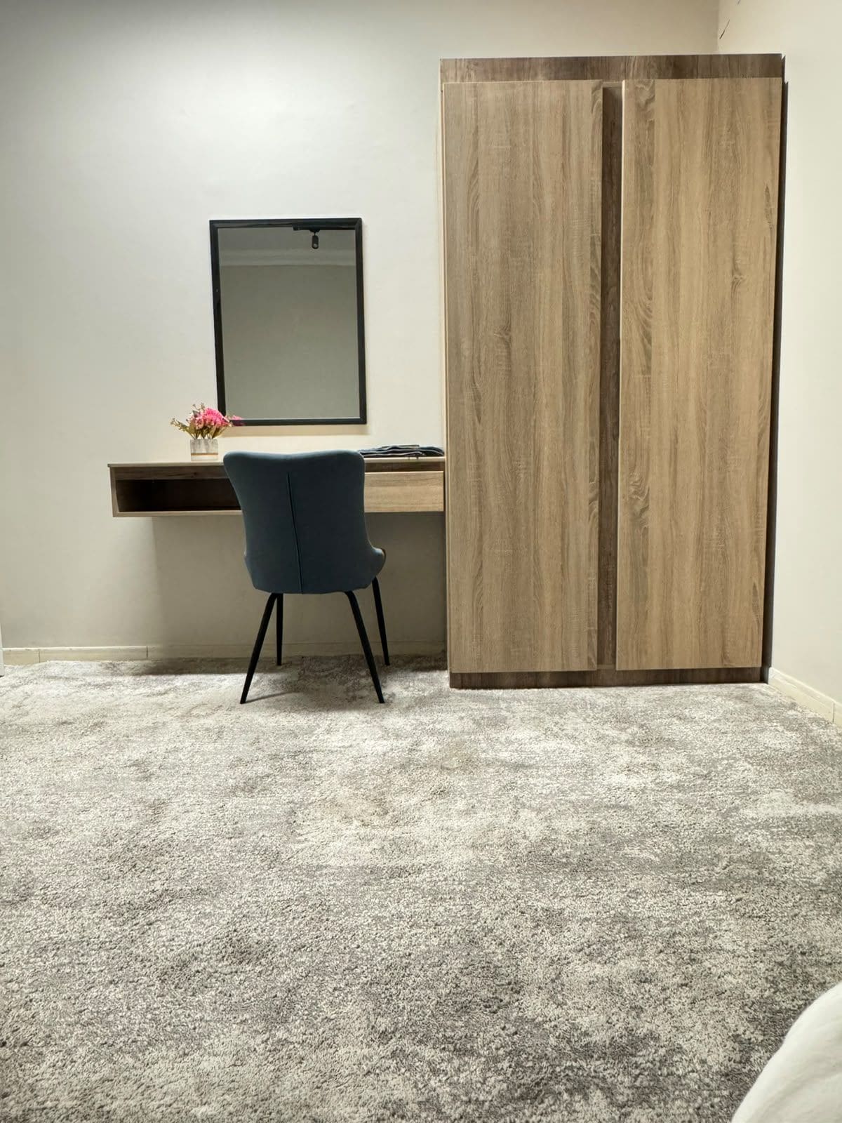 A room with a desk, chair, and wardrobe.