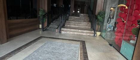 Un interior moderno con una escalera, un tapete estampado y una pared de vidrio con adornos rojos.