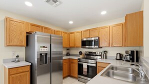 Una cocina moderna con armarios de madera, electrodomésticos de acero inoxidable y un microondas integrado.