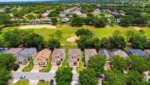 Vista aérea de una zona residencial con casas, un campo de golf y cielo despejado.