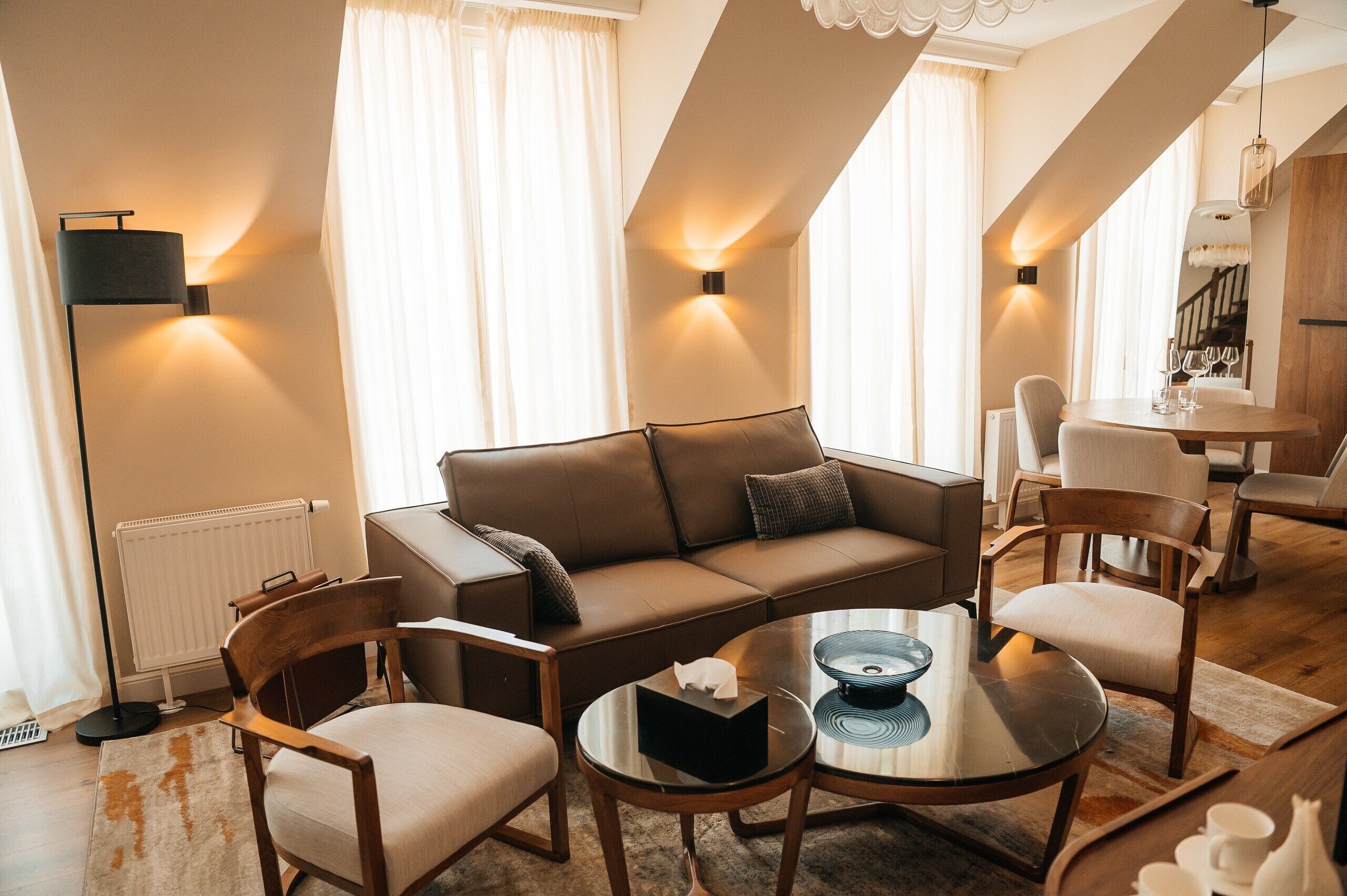 Ein modernes Wohnzimmer mit einer Couch, Sesseln, einem Couchtisch und einem Essbereich mit Tisch und Stühlen.