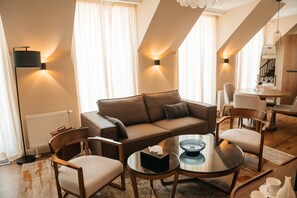 A modern living room with a sofa, chairs, a coffee table, and a dining area with a table and chairs.