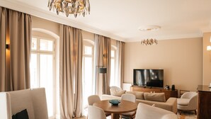 A spacious living room with a chandelier, a television, and a dining area with a round table.