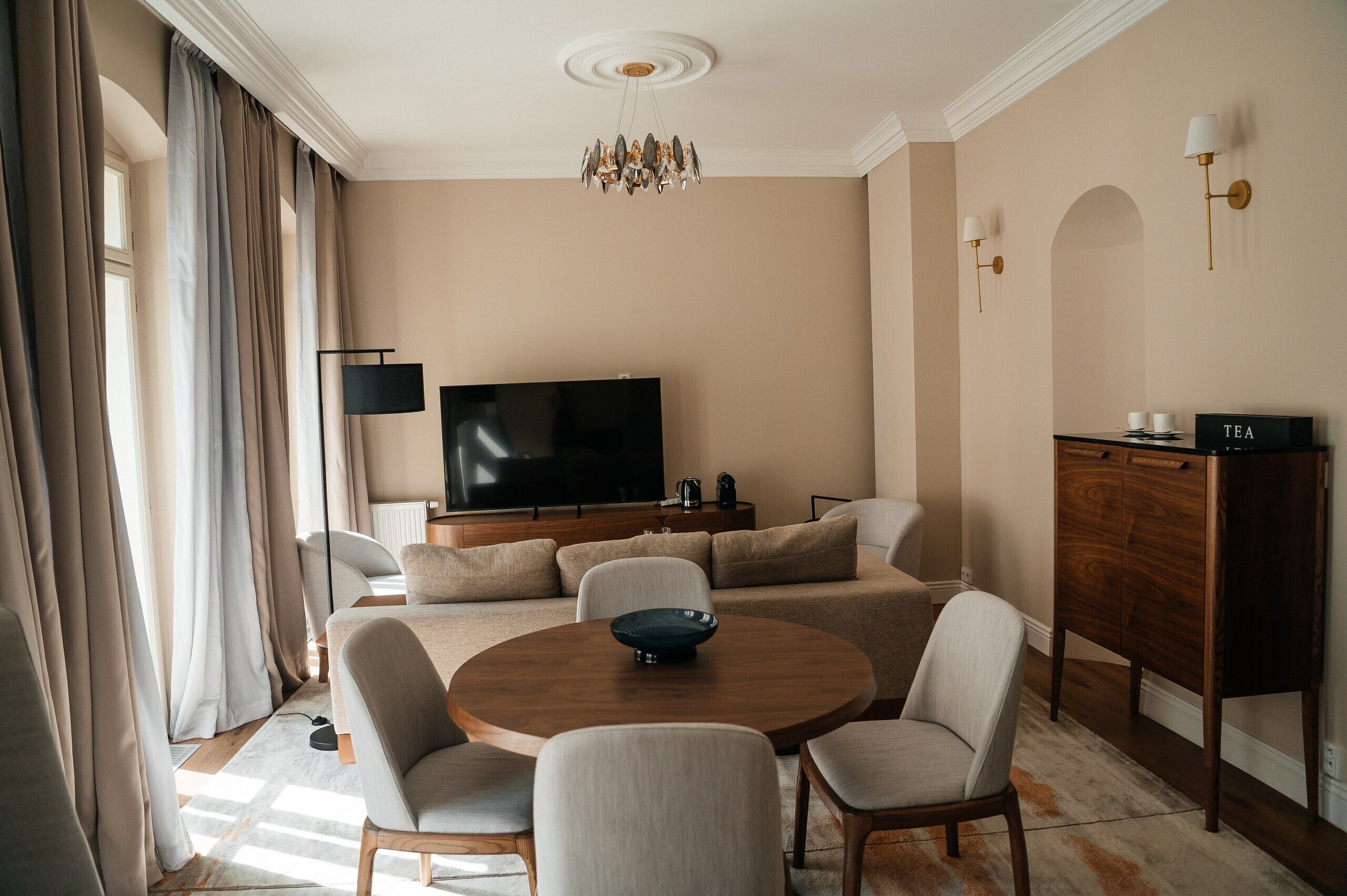 A modern living room with a flat-screen TV, a round wooden coffee table, and a sofa set.