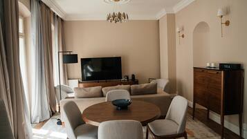 A modern living room with a flat-screen TV, a round wooden coffee table, and a sofa set.