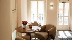 A hotel lobby with a round table, two chairs, a vase of flowers, and a door marked 'EXIT'.