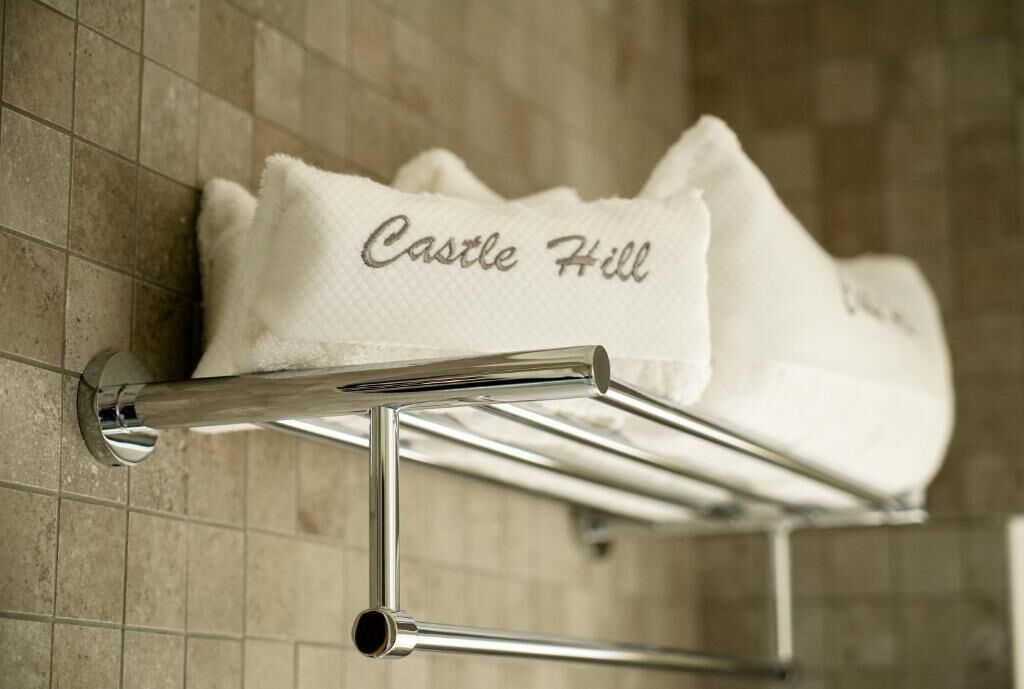 Un perchero con una toalla que dice 'Castle Hill' en un baño con paredes de azulejos.
