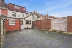 Ein Garten mit Terrasse, Holzzaun und einer separaten Garage.