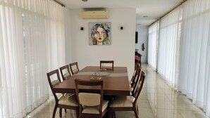 A dining area with a large table, chairs, and a painting on the wall.