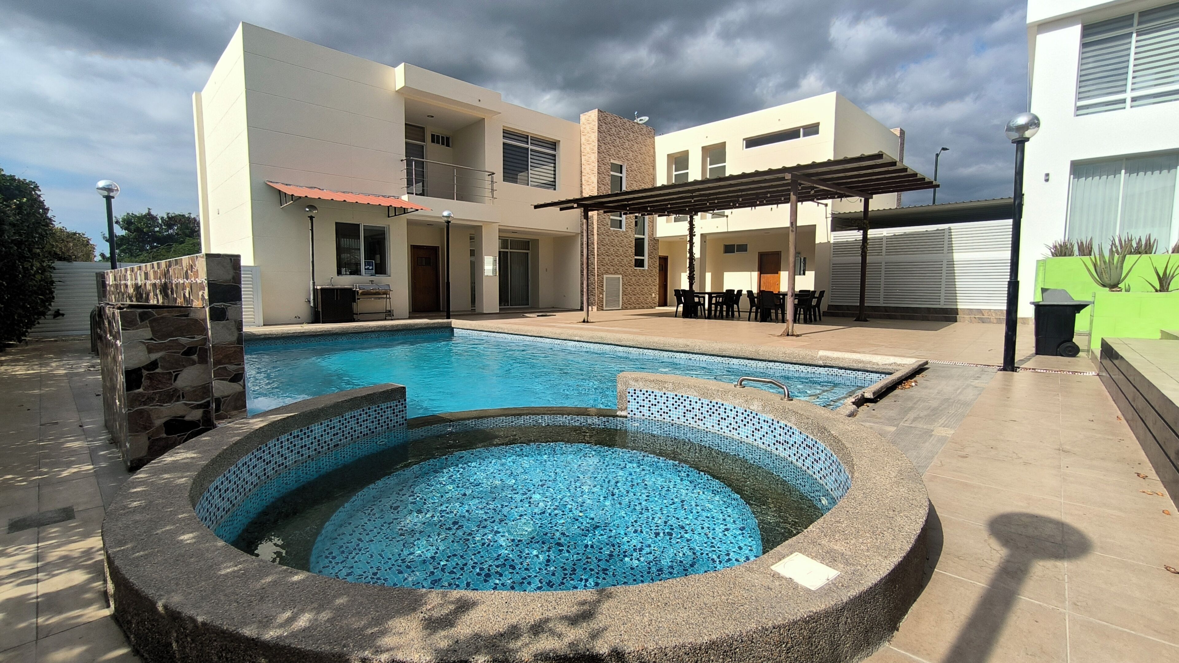 A swimming pool with a hot tub, surrounded by a patio area with outdoor furniture and a covered seating area.