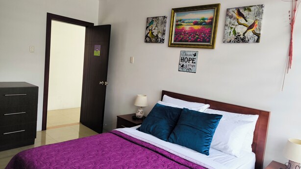 A hotel room with a bed, a dresser, a nightstand with a lamp, and artwork on the walls. - House with a private pool in the exclusive Montecristi Golf Resort & Villas (Montecristi)