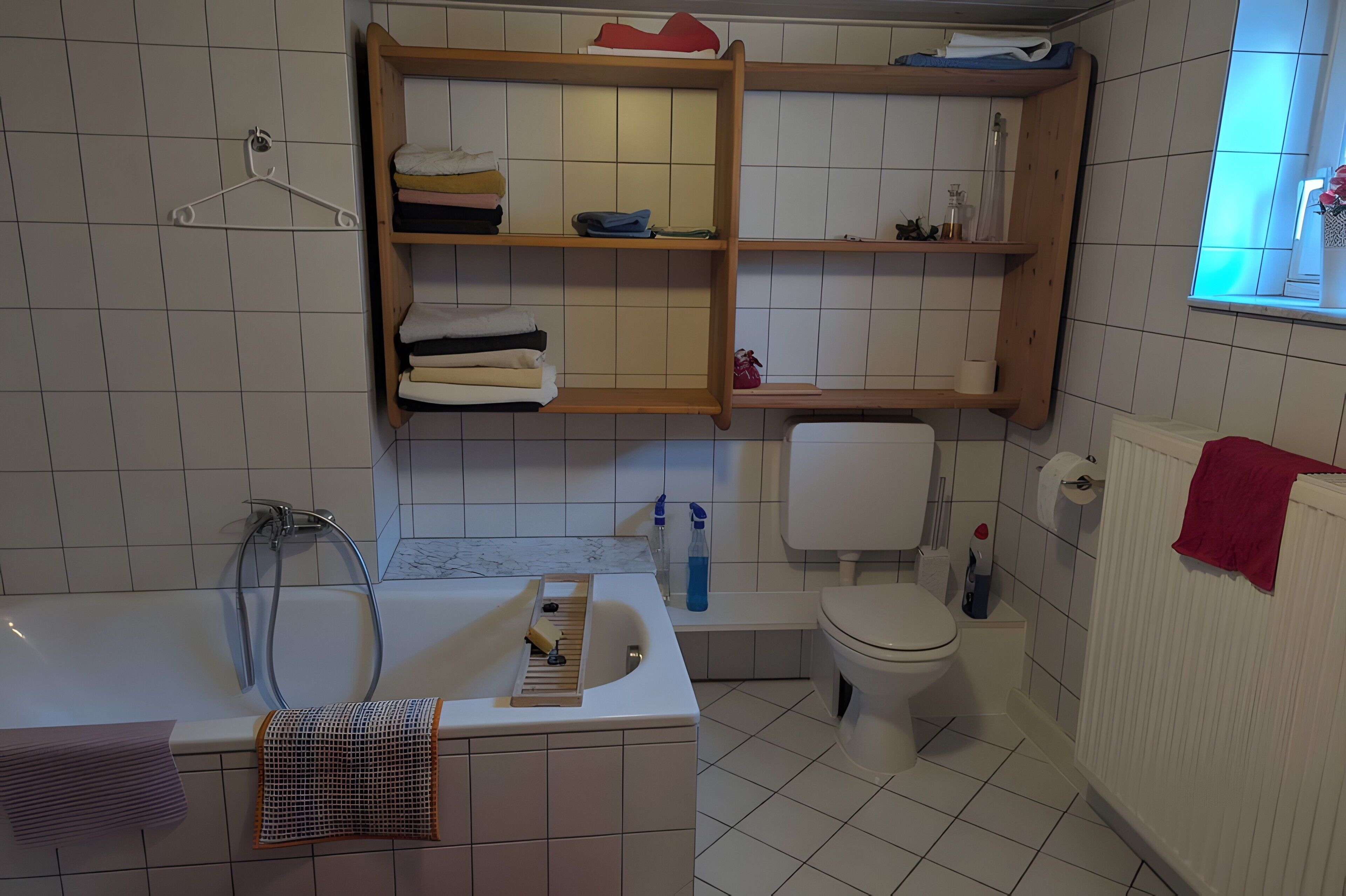A bathroom with a bathtub, toilet, and shelves with towels.