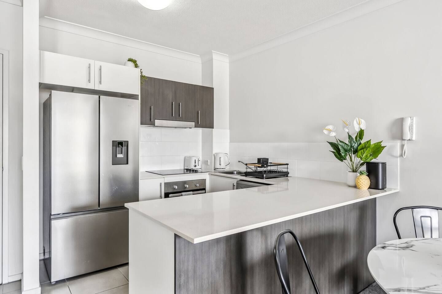 A modern kitchen with a central island, stainless steel appliances, and a dining area with a white table and chairs.