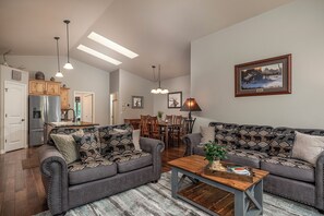 Una sala de estar con dos sofás, una mesa de centro y una zona de comedor con sillas y una mesa.