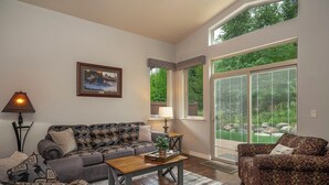 A living room with a sofa, armchair, coffee table, and a painting on the wall. - Golf Course Townhome 3 bed/3 bath, Private Hot Tub (Columbia Falls)
