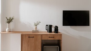 A minimalist room with a wooden cabinet, a television, and two vases with plants.