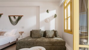 A modern bedroom with a bed, a sofa, a small round table, and wall-mounted decor.