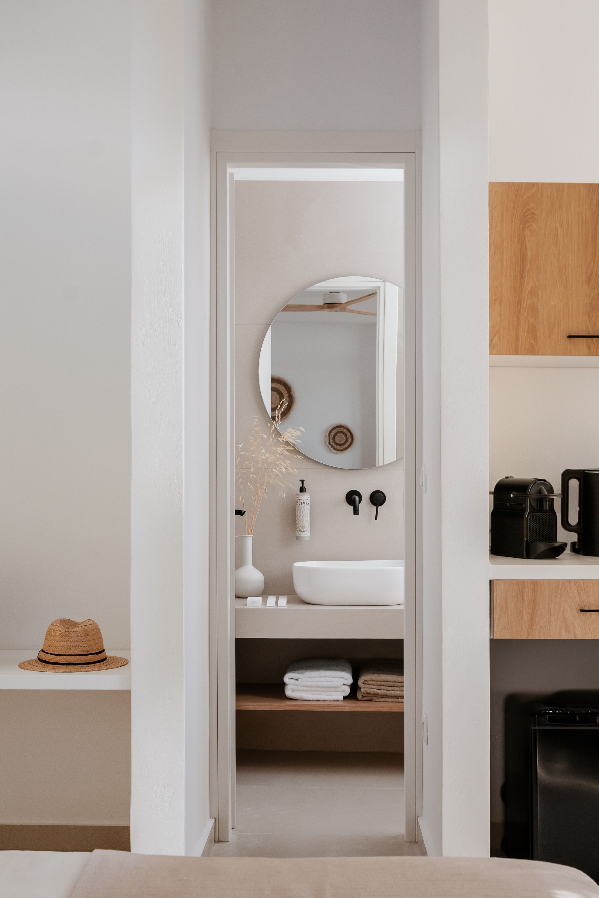 A narrow hallway leading to a bathroom with a white sink, mirror, and towel rack.