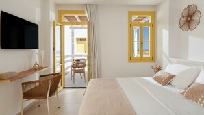 A bedroom with a bed, a TV mounted on the wall, a wooden desk, and a chair.