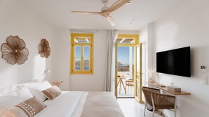 Ein Schlafzimmer mit Bett, Schreibtisch, Sessel, Fernseher und einem Balkon mit Blick.