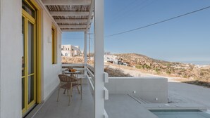 Ein Balkon mit Tisch und Stühlen, ein kleiner Pool und Blick auf den Strand und die Gebäude.