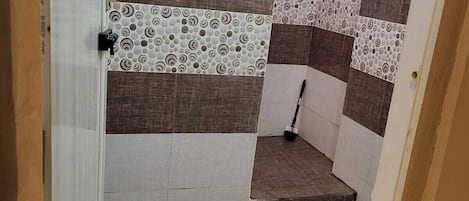 A bathroom with a tiled floor, a shower area, and a toilet.