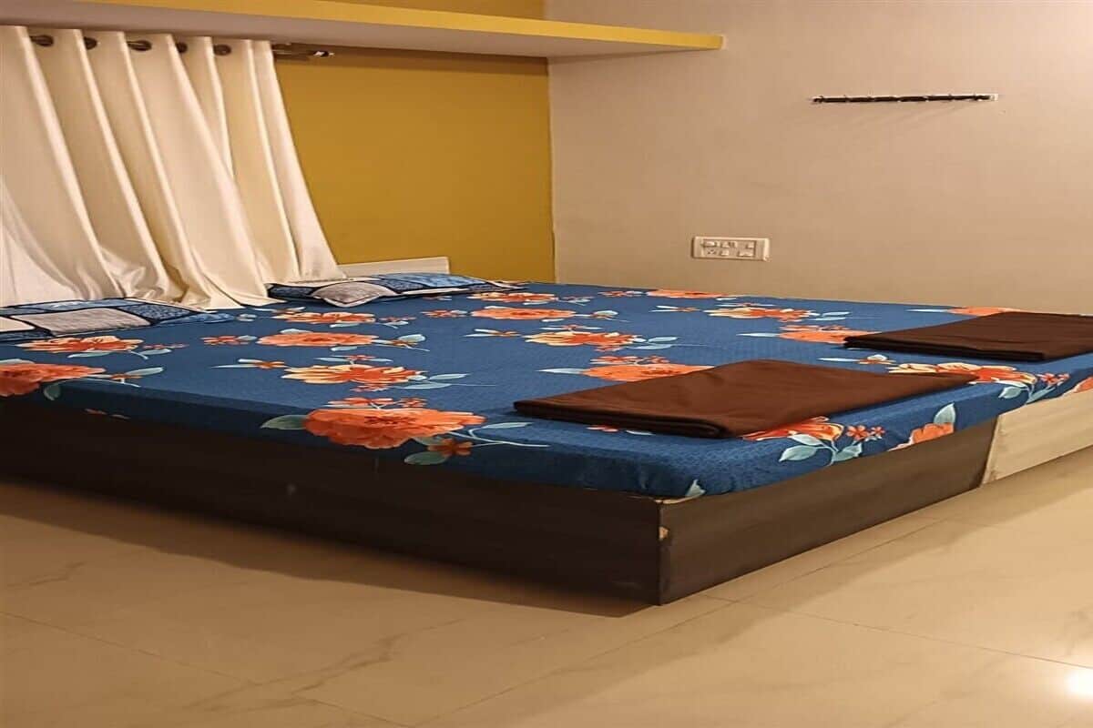 Una habitación con cama, cortina, toma de corriente e interruptor de luz.
