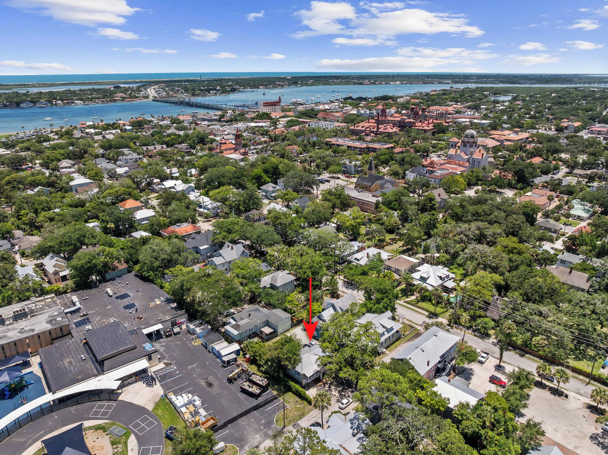 An aerial view of a coastal town with a marina, residential areas, and a large parking lot.