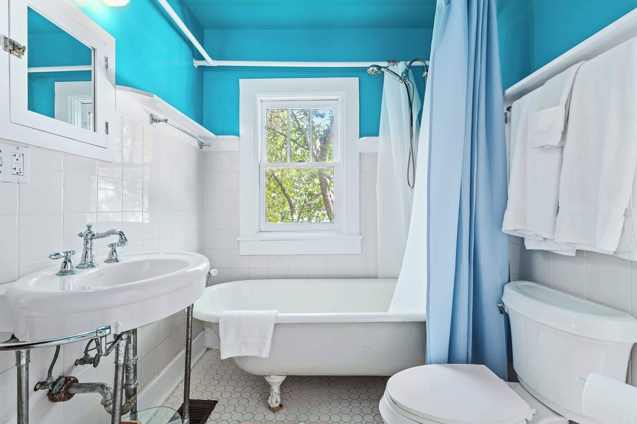 A bathroom with a bathtub, toilet, sink, and window.