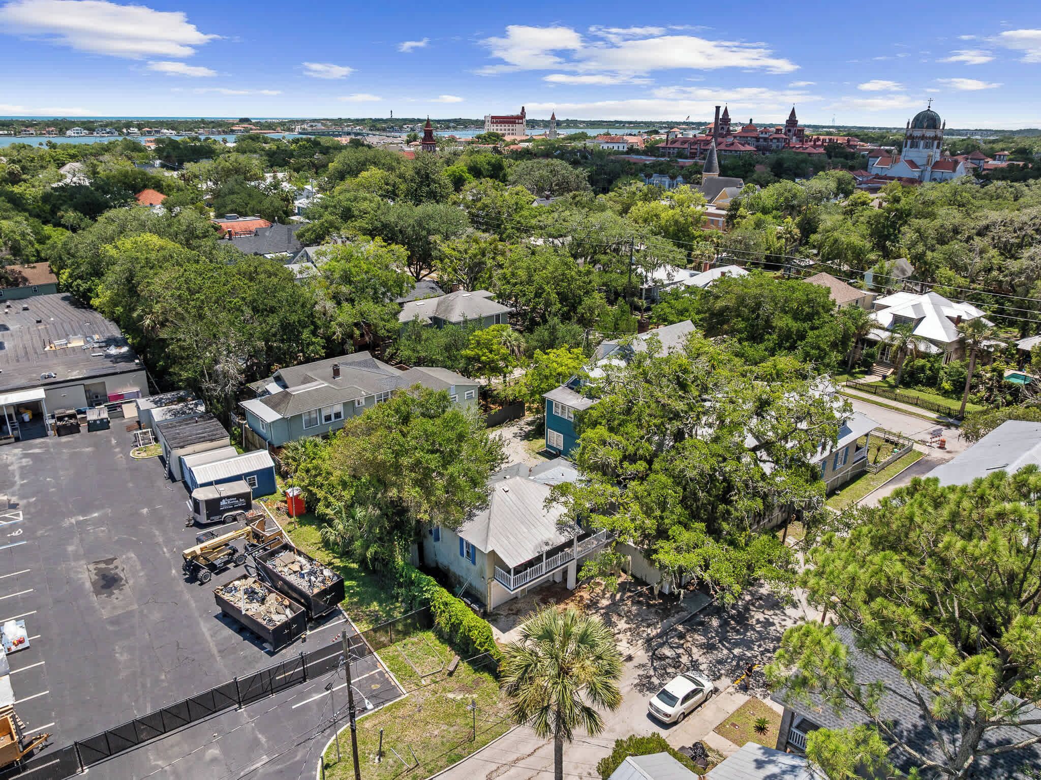 An aerial view of a residential area with houses, a parking lot, and a distant view of a town with historical buildings.