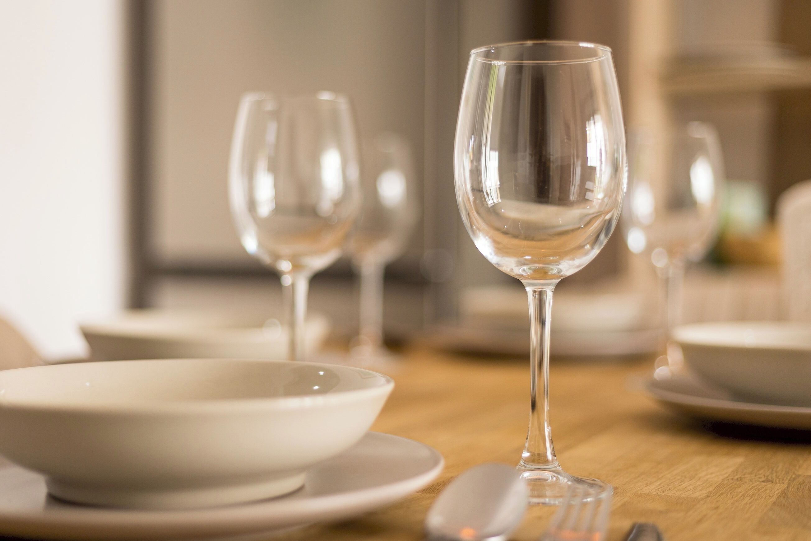 A dining table with clear glassware and white dinnerware.