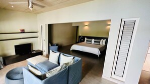 Una habitación de hotel moderna con sofá, cama, televisor y ventilador de techo.