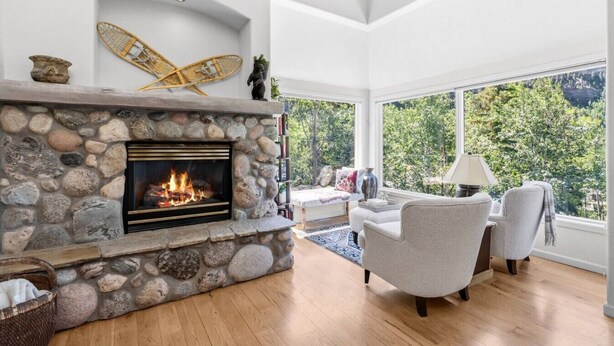 A room with a stone fireplace, a bed with a view, and a large window. - Gore Range Retreat I Mountain Views & Adventure (Vail)