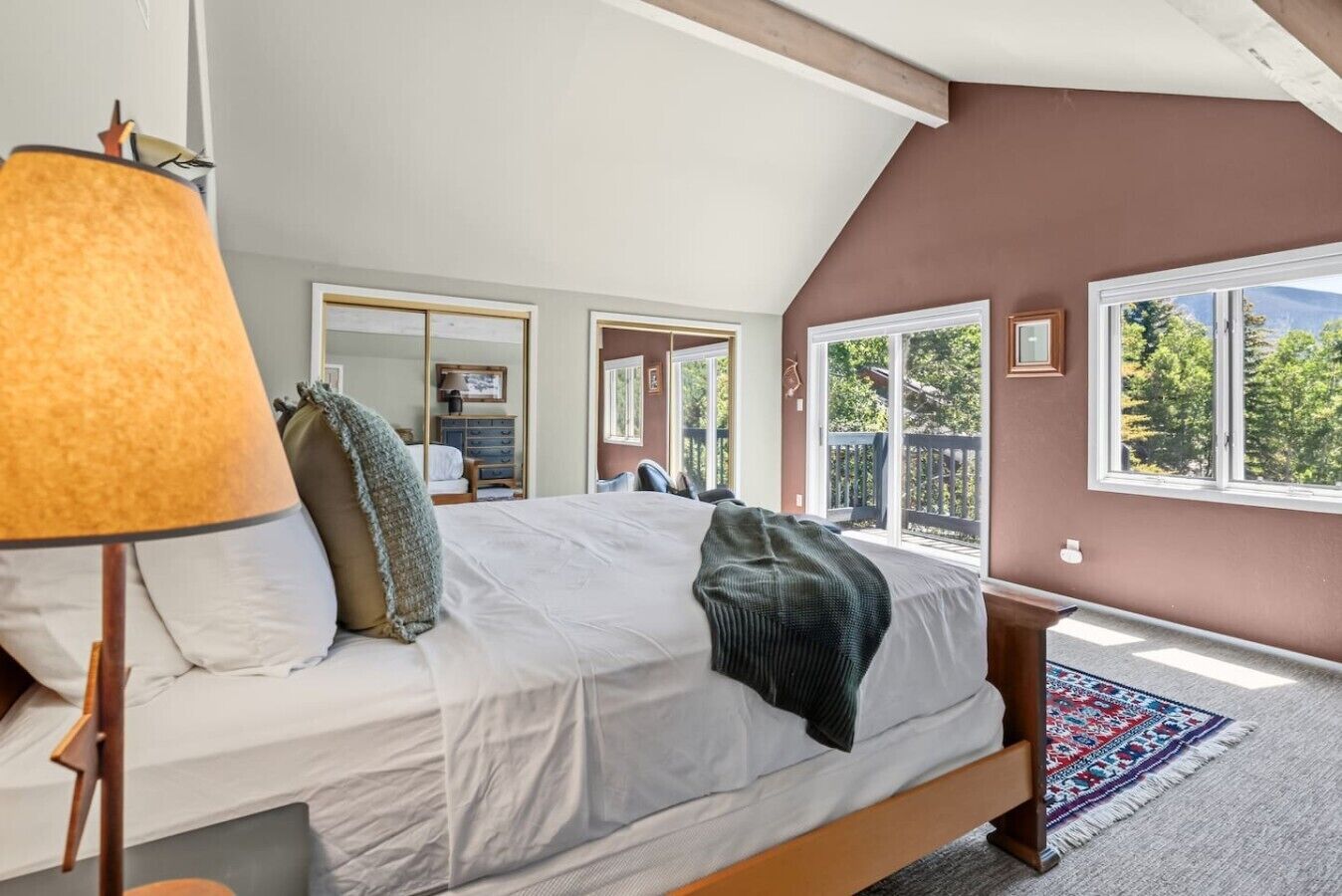 A bedroom with a large bed, a window, and a view of the outdoors.