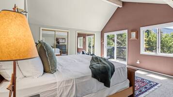 A bedroom with a large bed, a window, and a view of the outdoors.