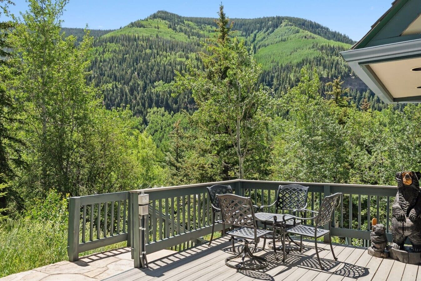 A deck with outdoor furniture and a view of forested mountains.