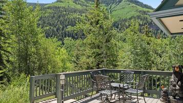 A deck with outdoor furniture and a view of forested mountains.