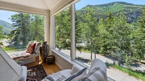 A room with a large window offering a view of a forested mountain range. - Gore Range Retreat I Mountain Views & Adventure (Vail)