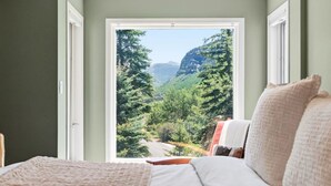 A bedroom with a large window offering a view of a forested valley. - Gore Range Retreat I Mountain Views & Adventure (Vail)